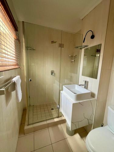 a bathroom with a shower and a sink and a toilet at Durban Suites at Oceanic in Durban