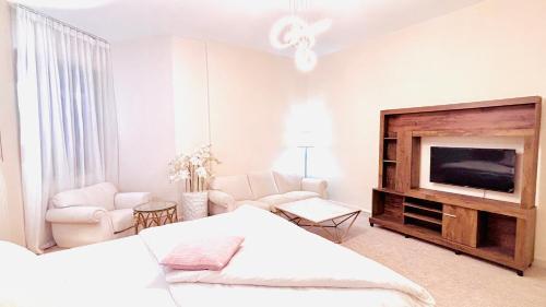 une chambre blanche avec un lit et une télévision dans l'établissement Sea View Holiday Home with Parking, à Ajman