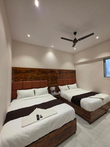um quarto com duas camas e um ventilador de teto em Hotel Powai Palace em Mumbai