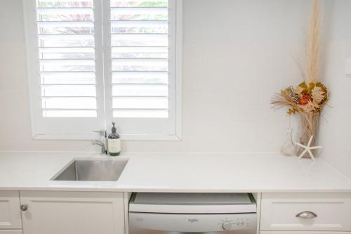 a white kitchen with a sink and a window at Balneaire 13 in Albany