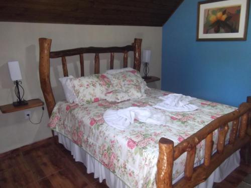 a bedroom with a wooden bed with a floral bedspread at Rancho Pôr Do Sol in Arapeí