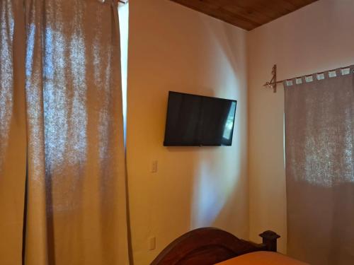 a bedroom with a tv on the wall and a curtain at La Casa Grande in San Cristóbal de Las Casas