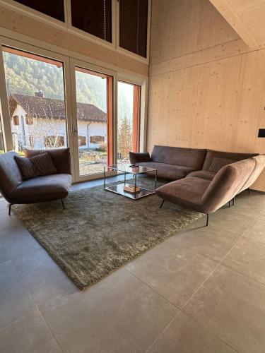 a living room with a couch and a glass table at Silenen Chalet I Andermatt I Ski I Berg I Familie in Silenen