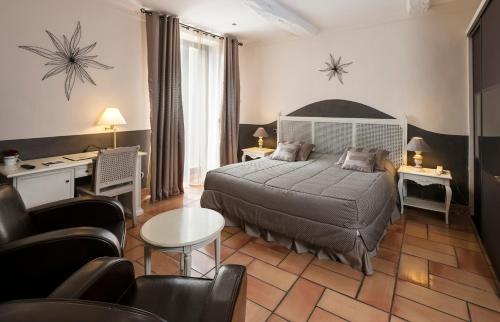 een slaapkamer met een bed, een bureau en stoelen bij Mas de Guilles in Lourmarin