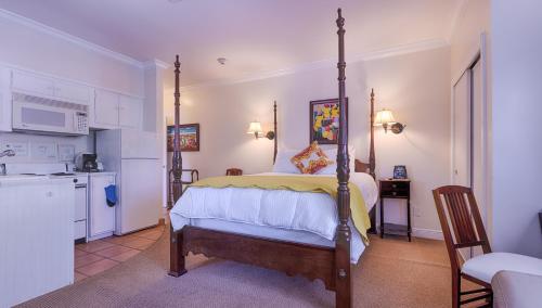 a bedroom with a four poster bed and a kitchen at The Caribbean Court Boutique Hotel in Vero Beach