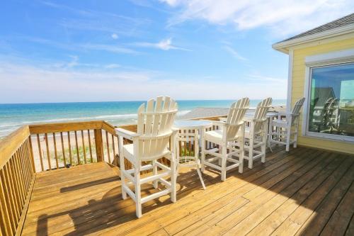 a deck with white chairs and a table and the ocean at Shore Bet in Surf City