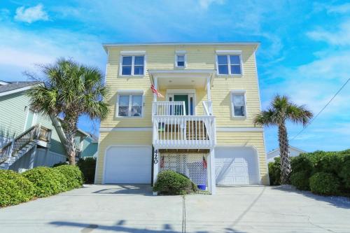 a yellow house with palm trees in front of it at Shore Bet in Surf City