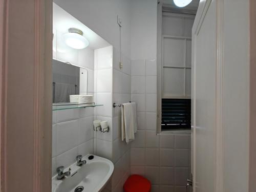 Mirasol Guesthouse في فونشال: حمام أبيض مع حوض ومرآة