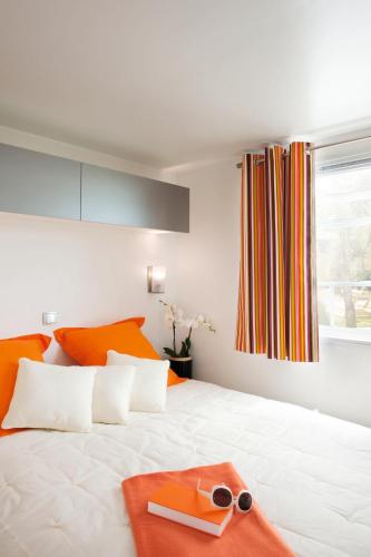 a white bed with orange pillows and a tray on it at Paradis Des Dombes in Sandrans