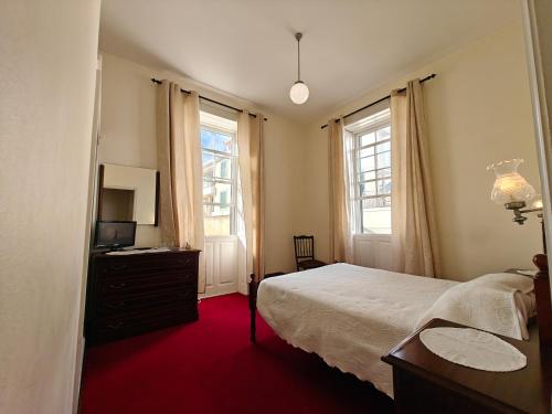 Mirasol Guesthouse في فونشال: غرفة نوم بسرير وخزانة ونوافذ