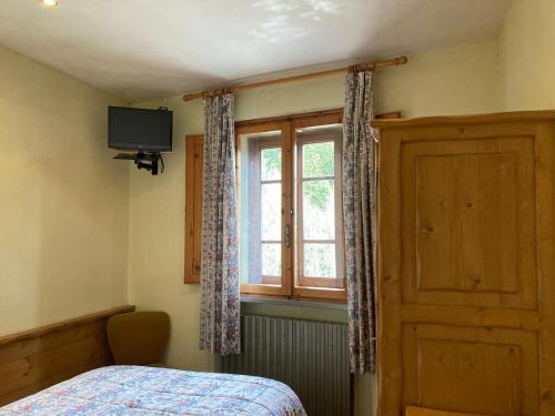 ein Schlafzimmer mit einem Bett und einem Fenster und einem Fernseher in der Unterkunft B B Regina in Abetone