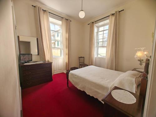 a bedroom with a bed and a tv and windows at Mirasol Guesthouse in Funchal