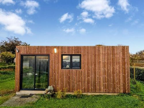 a small wooden house with windows in the grass at Le chalet à bulles in Sainte-Marie-au-Bosc