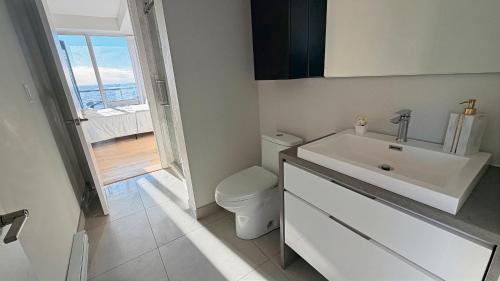 ein weißes Badezimmer mit Waschbecken und Toilette in der Unterkunft Panoramic Horizon Condo - Downtown Montreal with Pool and Parking in Montreal