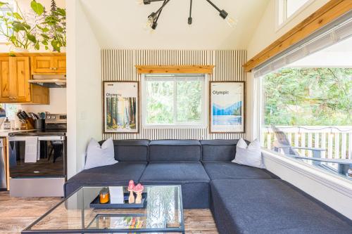 uma sala de estar com um sofá azul e uma mesa de vidro em NEW Nestled Private Tiny Home Situated Near ONP em Port Angeles