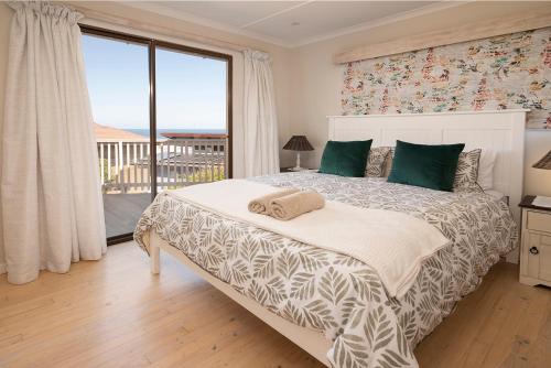a bedroom with a large bed with a large window at Leef op Hoop in Boggomsbaai