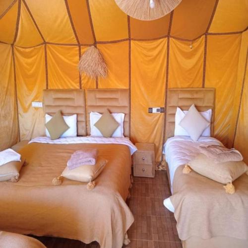 a bedroom with two beds in a tent at Unique Sahara Camp in Merzouga