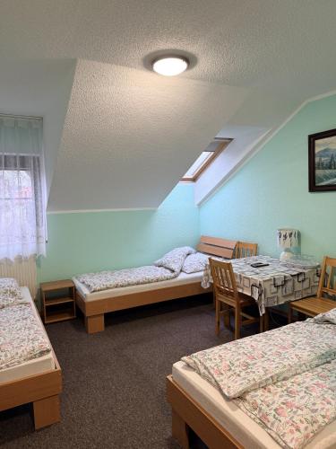 a room with three beds and a table and chairs at Pokoje Gościnne Stawiguda in Stawiguda