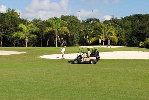un carro de golf estacionado en un campo de golf en Departamento cerca del mar en Puerto Aventuras #104, en Puerto Aventuras