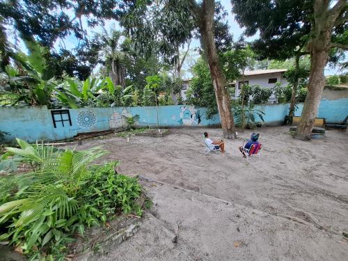 塞古罗港Pousada Alto Mar Hostel Camping的两个人坐在院子里的椅子上，院子里有树