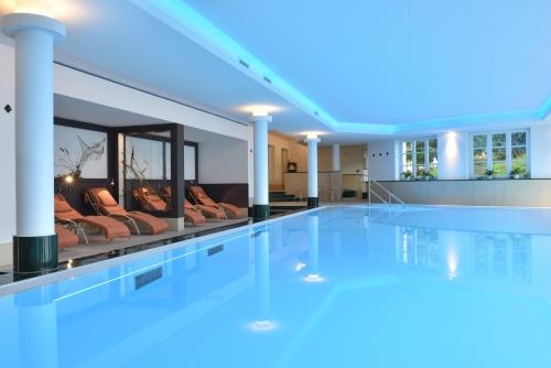 a swimming pool in a house with couches at Romantik Hotel Fischerwiege in Ahrenshoop