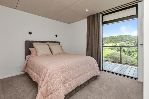 um quarto com uma cama e uma janela grande em The Pods - Tutukaka Coast Holiday Home em Ngunguru