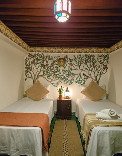 two beds in a room with floral wallpaper at Riad Dalia - Fes Medina in Fez