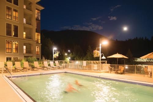 a swimming pool with two people in it at night at Pan Pacific Whistler Mountainside in Whistler