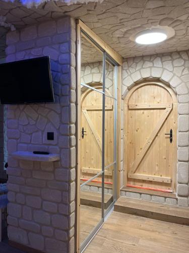 a room with two wooden doors and a tv on a wall at Leśna Grota na Roztoczu in Górecko Stare