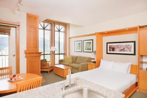 a hotel room with a bed and a living room at Pan Pacific Whistler Mountainside in Whistler