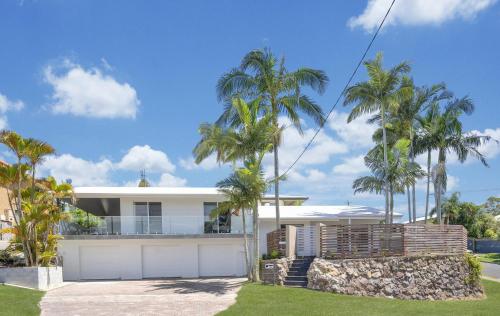 a white house with palm trees in front of it at Goonawarra Getaway at Mooloolaba in Mooloolaba