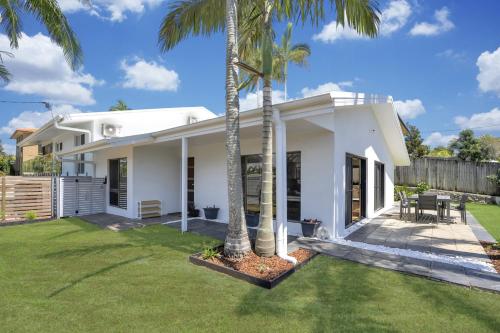 a white house with palm trees in the yard at Goonawarra Getaway at Mooloolaba in Mooloolaba