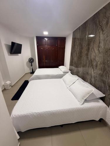 a bedroom with two beds and a flat screen tv at Lumière House in Medellín