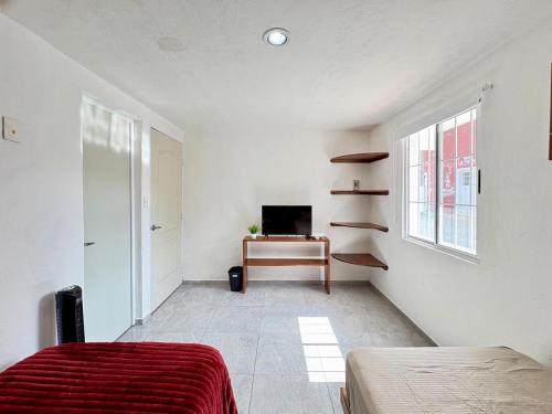 ein Schlafzimmer mit Bett, Schreibtisch und Fenster in der Unterkunft Monet Hotel Motul in Motul de Felipe Carrillo Puerto