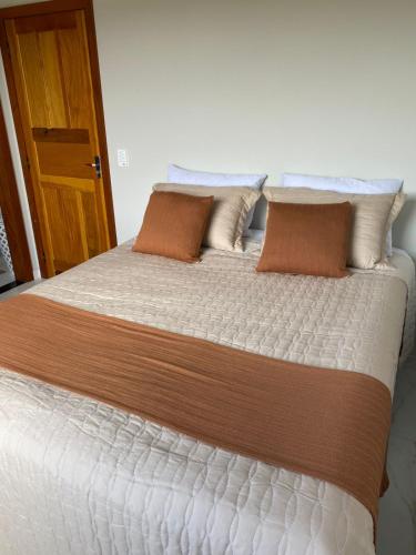 a large bed with brown and white sheets and pillows at Estância da Colina Chalet in Venda Nova do Imigrante
