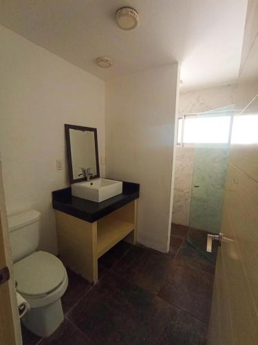 a bathroom with a sink and a toilet and a mirror at Departamento cerca del mar en Puerto Aventuras #105 in Puerto Aventuras