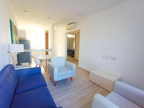 Una sala de estar con un sofá azul y una mesa. en Departamento cerca del mar en Puerto Aventuras #105, en Puerto Aventuras