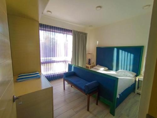 Un dormitorio con una cama y un banco y una ventana. en Departamento cerca del mar en Puerto Aventuras #105, en Puerto Aventuras