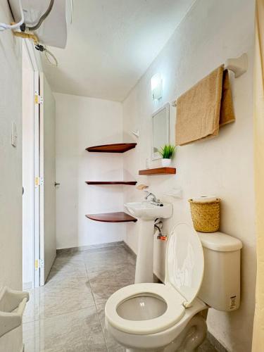 ein Badezimmer mit Toilette, Waschbecken und Regalen in der Unterkunft Monet Hotel Motul in Motul de Felipe Carrillo Puerto