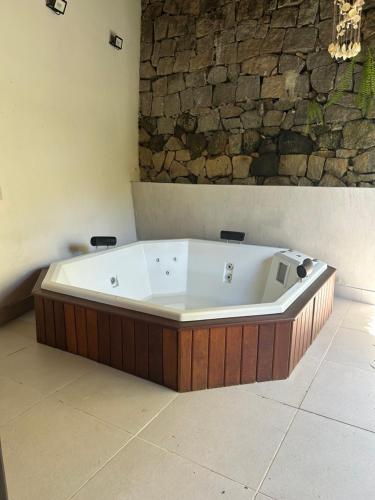 eine Badewanne in einem Raum mit einer Steinwand in der Unterkunft Angra dos Reis - Píer 600 casa 4 in Angra dos Reis