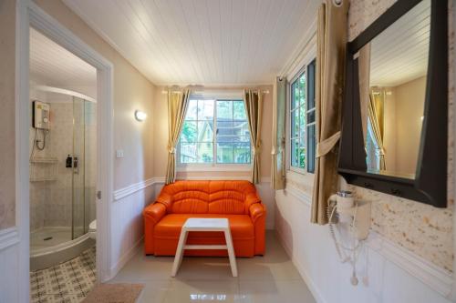 Puprai Tarnnarm Resort في ثونغ فا فوم: أريكة برتقالية في الحمام مع نافذة