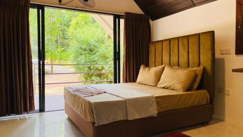 a bedroom with a large bed with a large window at Seravelle Kitulgala in Kitulgala