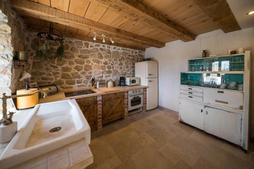 a kitchen with white appliances and a stone wall at Villa Natalia in Grižane