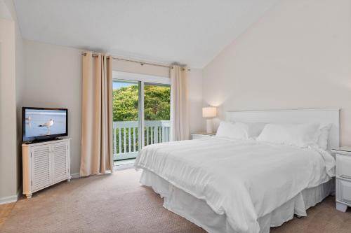 ein weißes Schlafzimmer mit einem Bett und einem Fernseher in der Unterkunft Ocean Glen 8 Sea Clearly in Salter Path