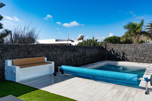 ein Schwimmbecken mit einer blauen Schwimminsel neben einer Wand in der Unterkunft Villa Cactus - Large Private Plot - Heated Pool & BBQ - Luxury Vacation in Playa Blanca
