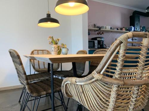 un tavolo da pranzo con sedie in vimini e luci di Pina Hideaway with a sea view rooftop terrace a Bicas