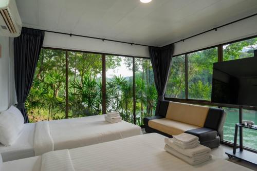 Puprai Tarnnarm Resort في ثونغ فا فوم: غرفة نوم بها سريرين ونافذة كبيرة