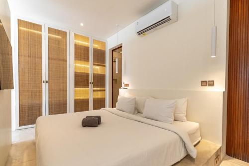 een slaapkamer met een wit bed met een zwarte tas erop bij Sore Pererenan Residence Unit 3 in Canggu