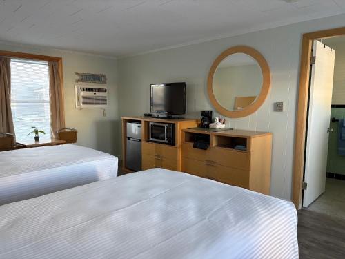 旧奥查德比奇Moontide Motel, Apartments, and Cabins的有两张床和一面镜子的酒店房间