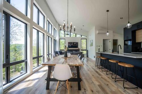 a kitchen and dining room with a wooden table and chairs at Chalet Le Greenwood - Mountain View & Private Spa in Saint-Faustin